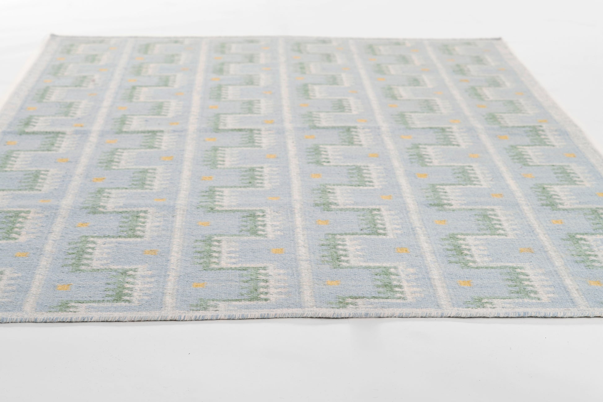 Flatwoven blue and cream geometric rug with tiny orange accents in a Scandinavian-inspired pattern.