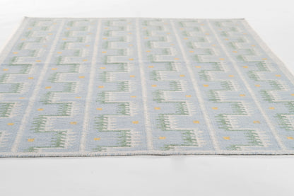 Blue & pale gray Scandinavian-style flatweave rug with repeating geometric square blocks & small yellow accents.