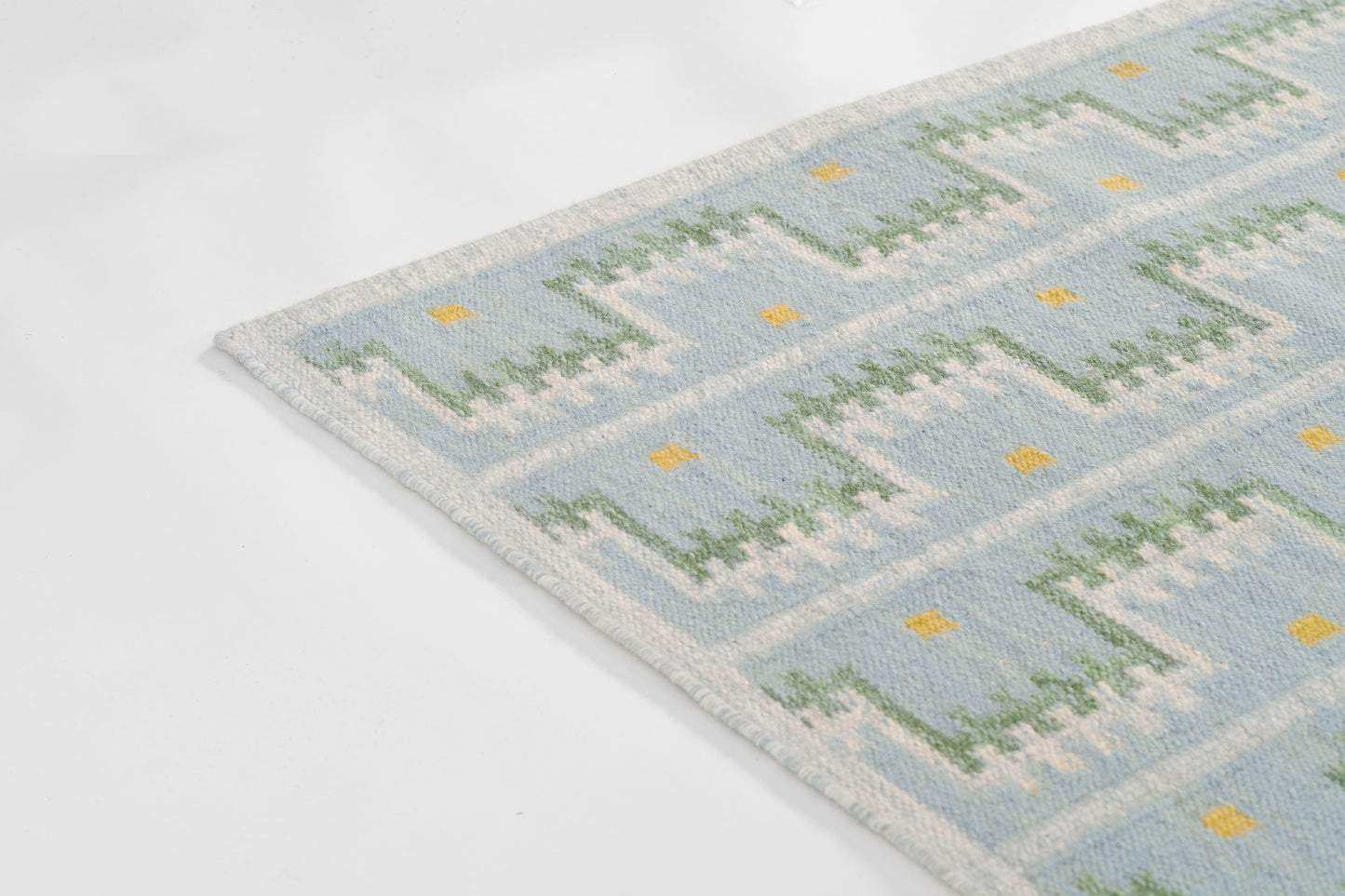 Blue Scandinavian-style woven rug with light blue base, mint green geometric blocks and small yellow accents.