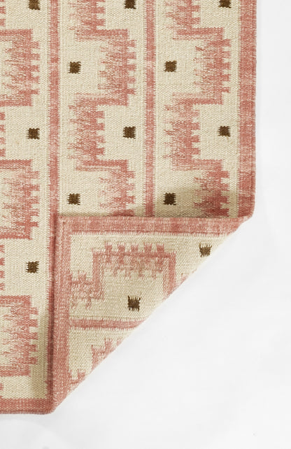 Scandinavian-inspired cream rug with pink geometric motifs and small brown squares; woven texture, folded corner.