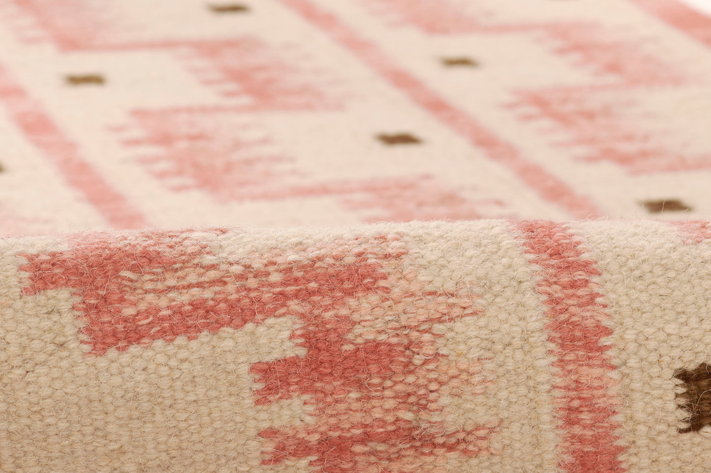 Beige woven rug with pink geometric motifs and a soft, textured Nordic-inspired finish.
