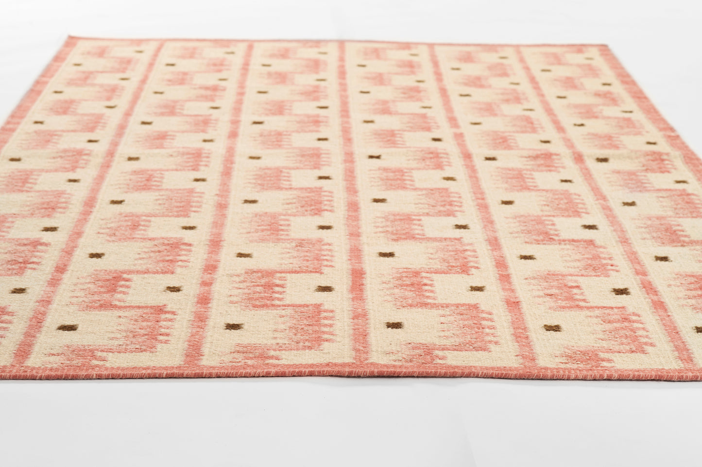 Scandinavian-style flat-weave rug with peach-pink geometric blocks on a cream background.