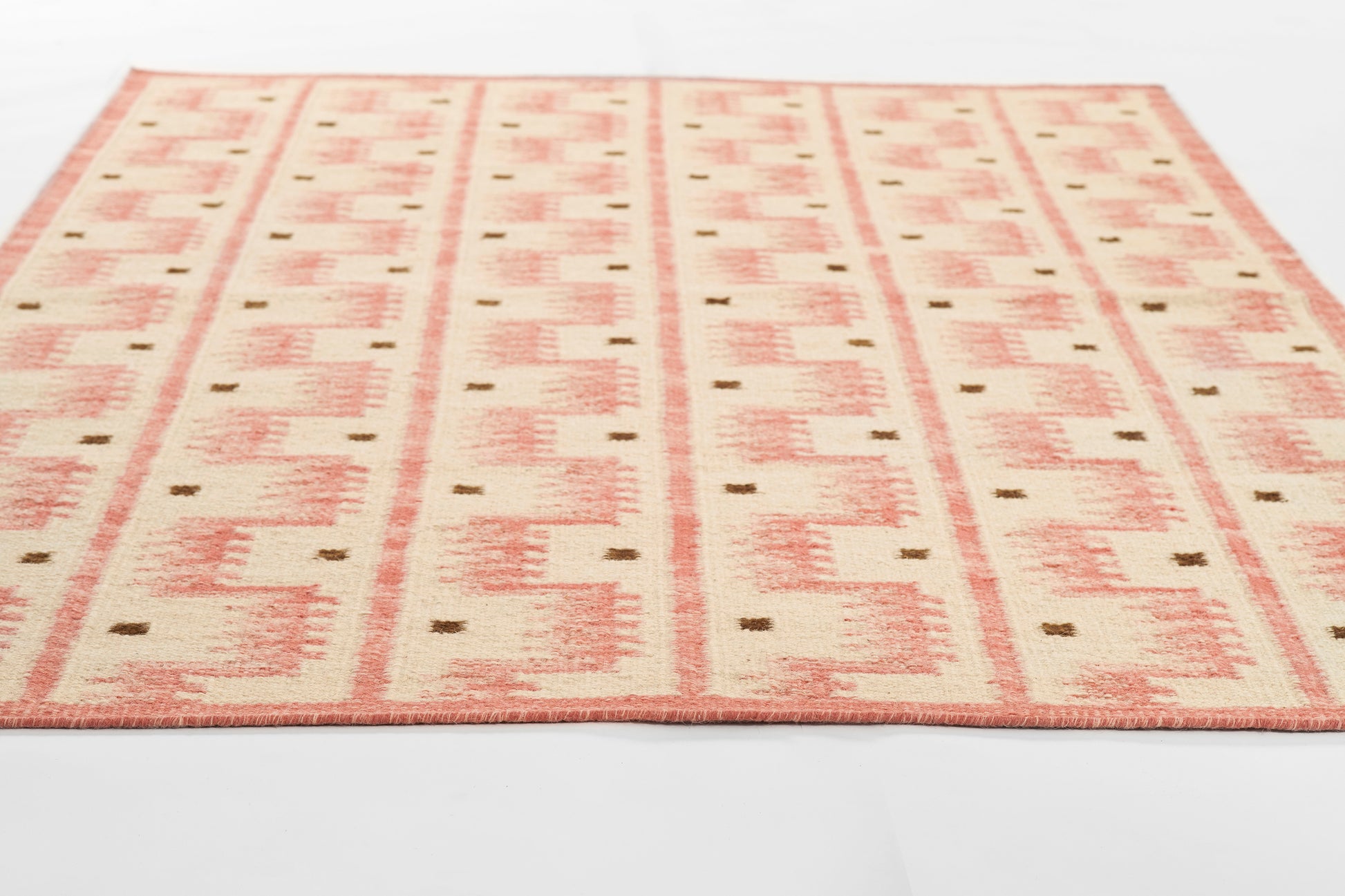 Scandinavian-style flat-weave rug with peach-pink geometric blocks on a cream background.