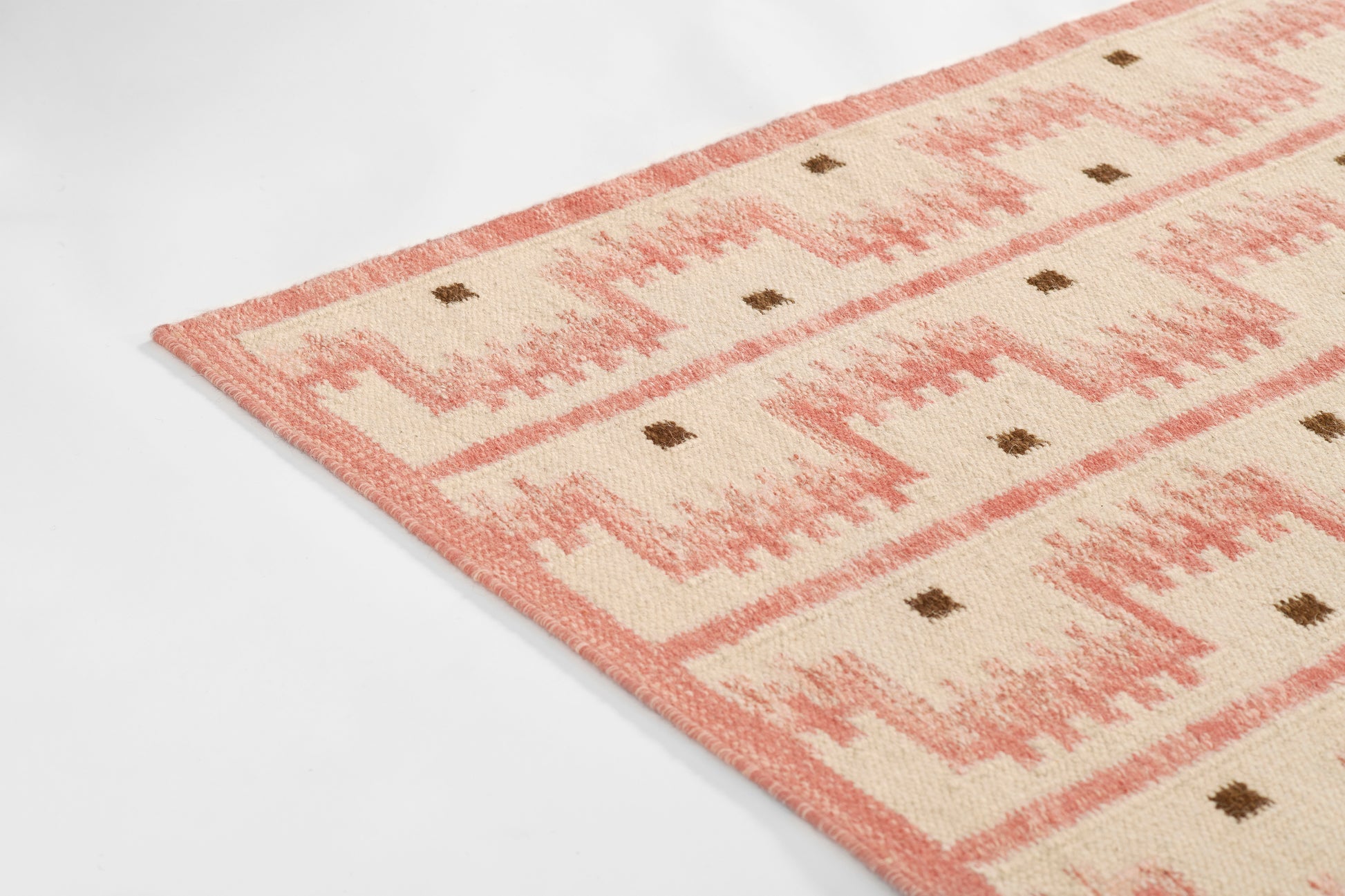 Rectangular pink and ivory geometric Scandinavian rug, woven texture with small brown diamond accents.