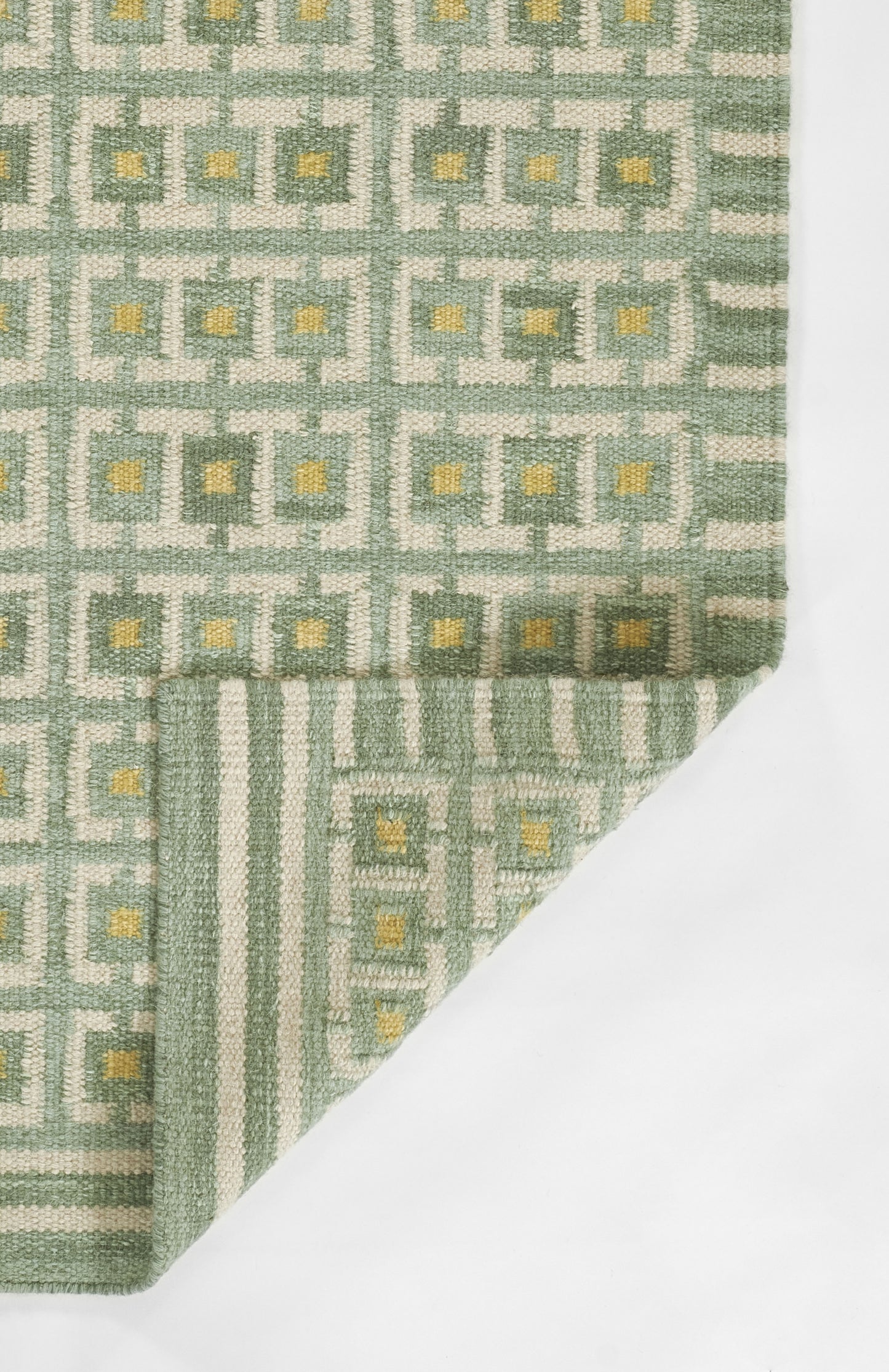 Green and gray Scandinavian geometric print fabric with small yellow centers; folded corner reveals striped underside.