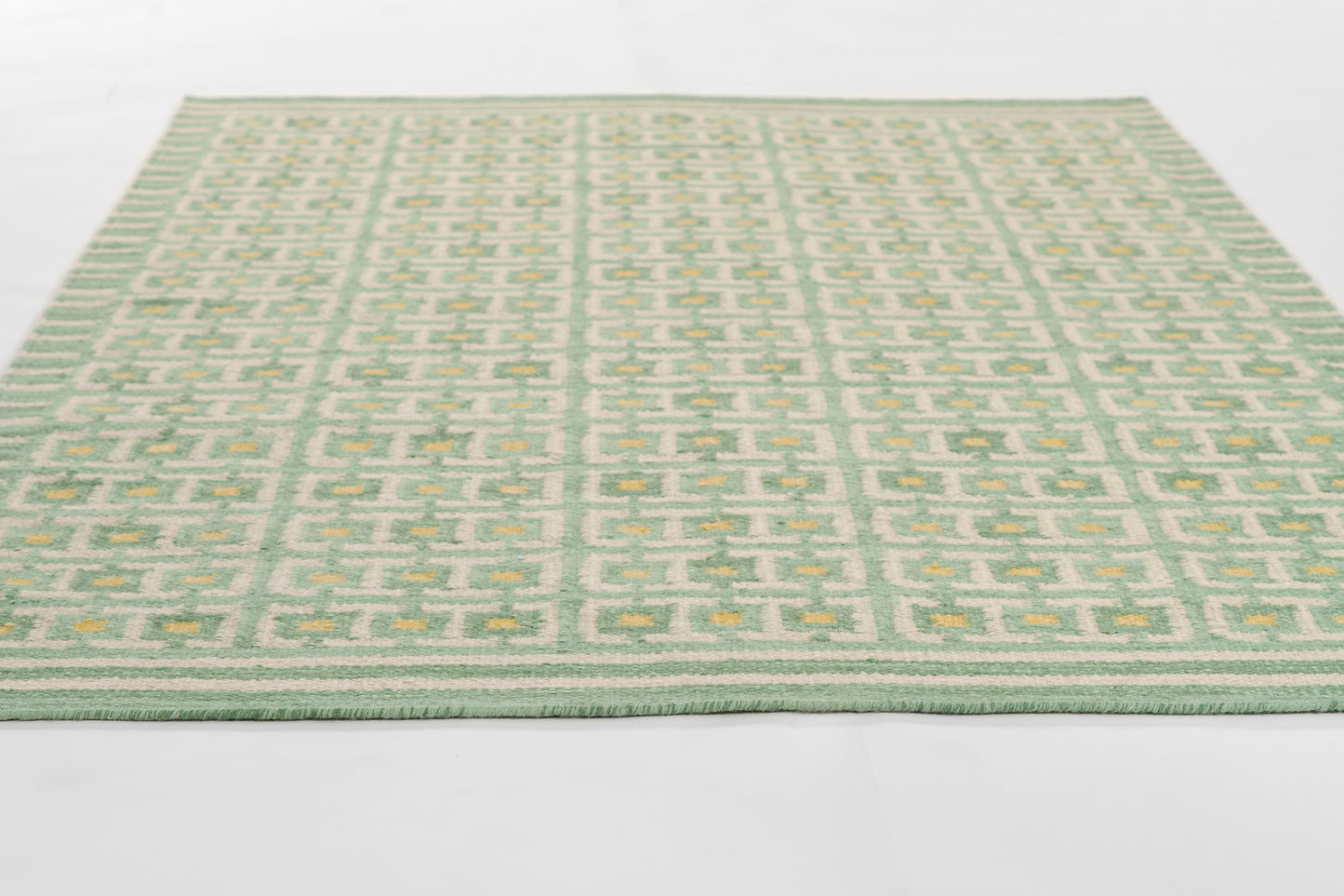 Rectangular green rug with cream geometric lattice pattern; flat-woven look, ideal for living room or hallway.