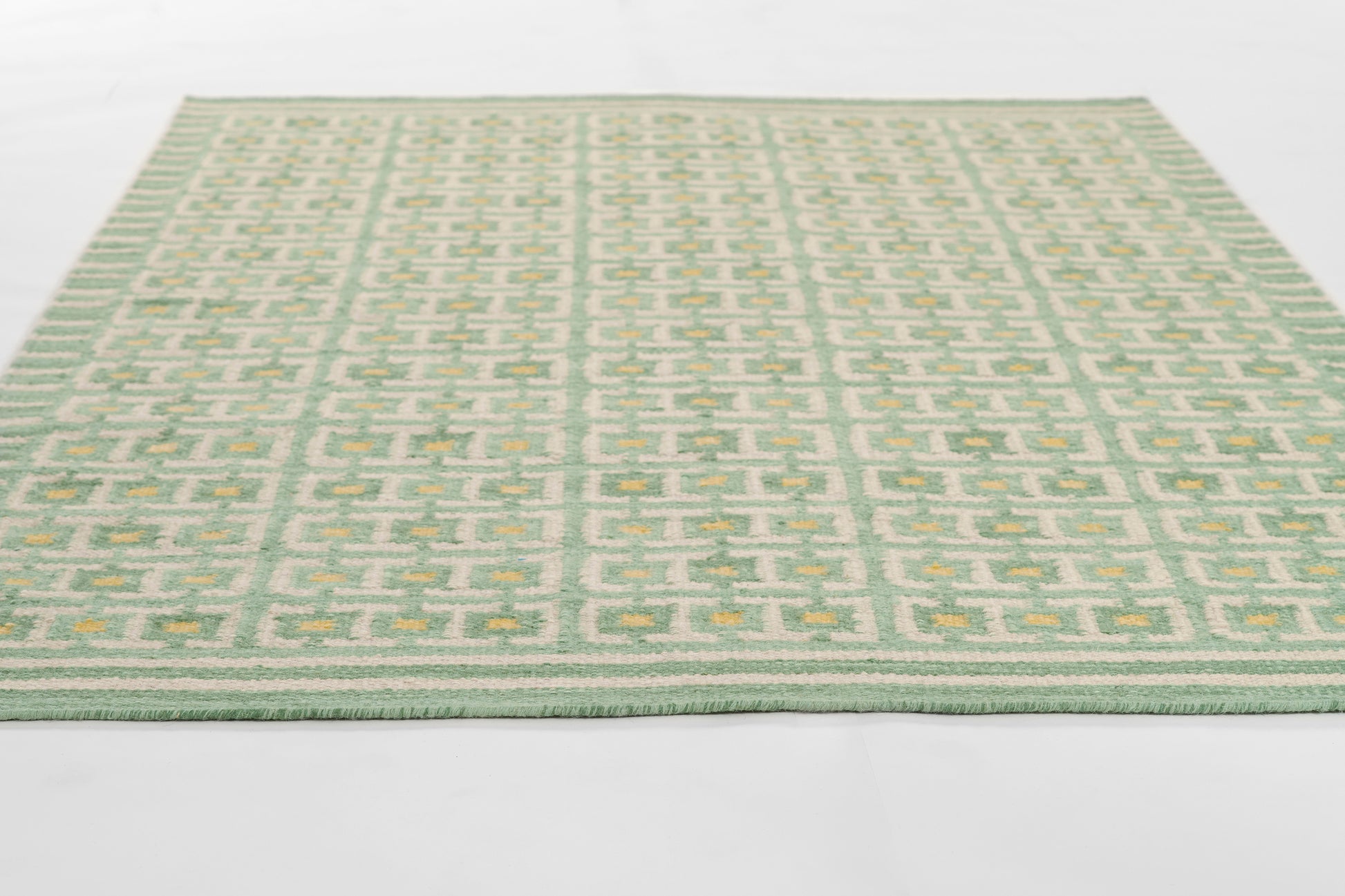 Scandinavian-style mint green rug with pale beige-green geometric lattice pattern; flat-weave rectangular area rug.