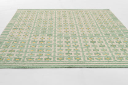 Flatwoven rug in sage green and pale yellow with a geometric trellis pattern; rectangular, modern Scandinavian style.
