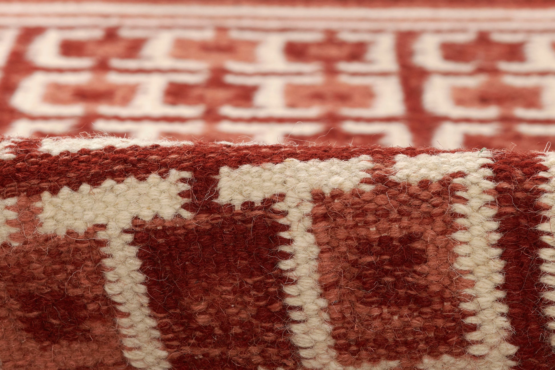 Close-up of a red and white Scandinavian woven wool rug runner with chunky texture and geometric pattern.