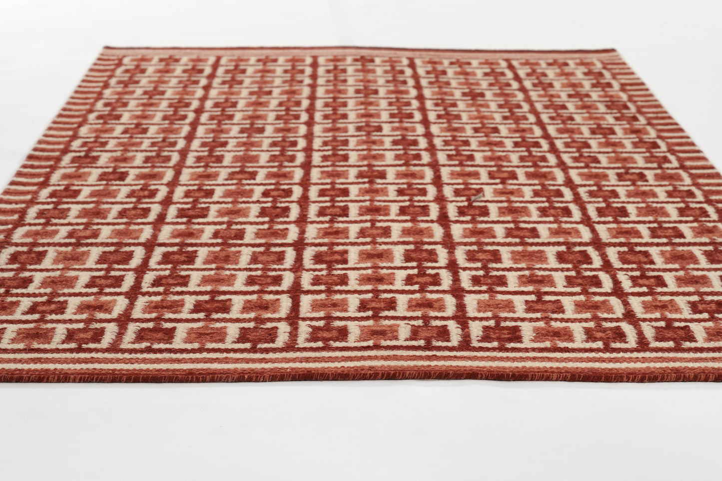 Rectangular red and cream woven rug with repeating geometric pattern, Scandinavian-inspired design.