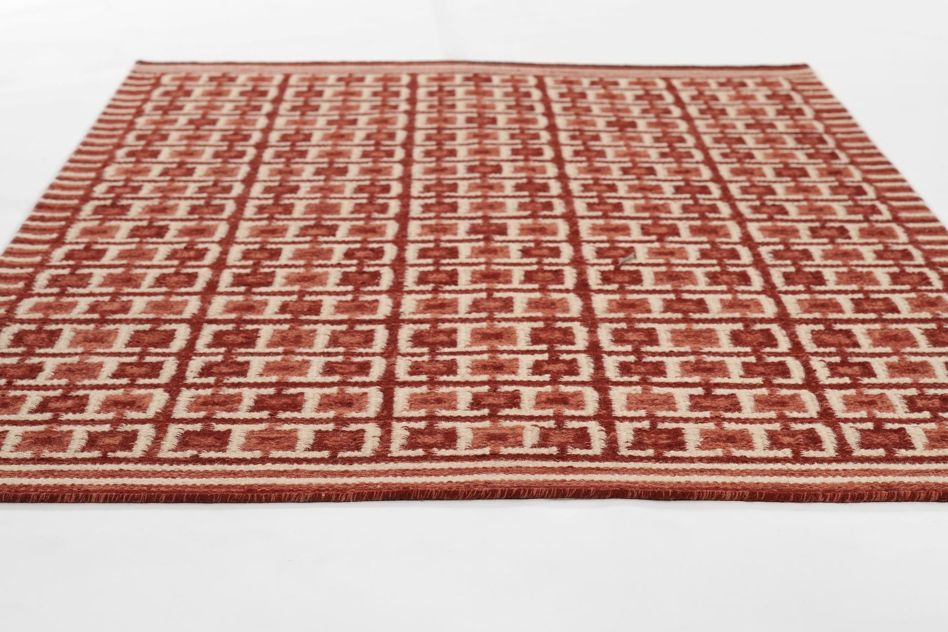 Rectangular red and cream woven rug with repeating geometric pattern, Scandinavian-inspired design.