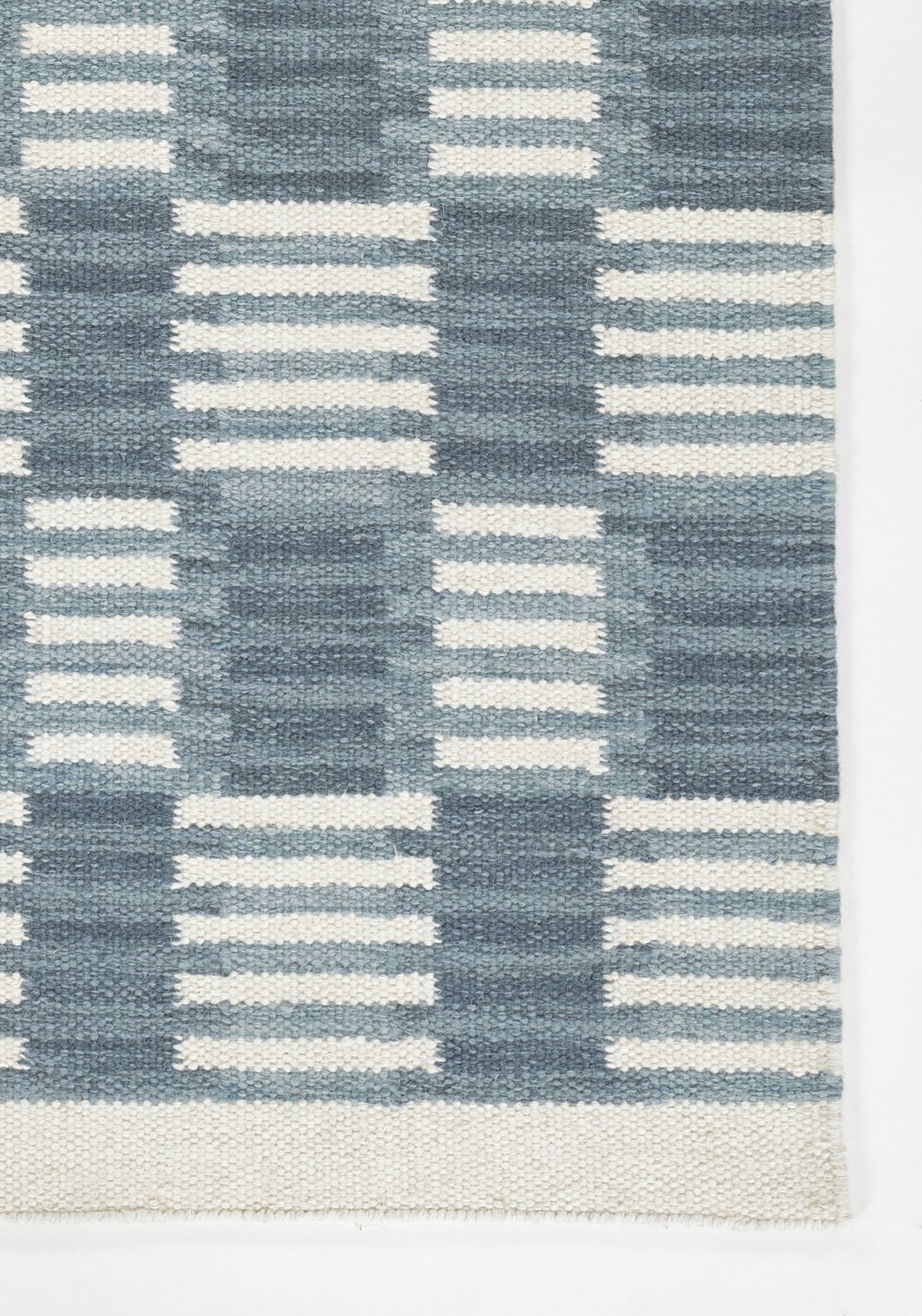 Scandinavian blue and white woven rug with geometric pattern and fringe.