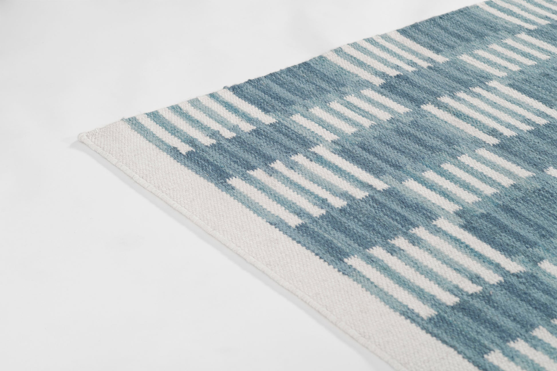 Blue and white plaid woven rug with beige edge, Scandinavian-inspired decor textile.