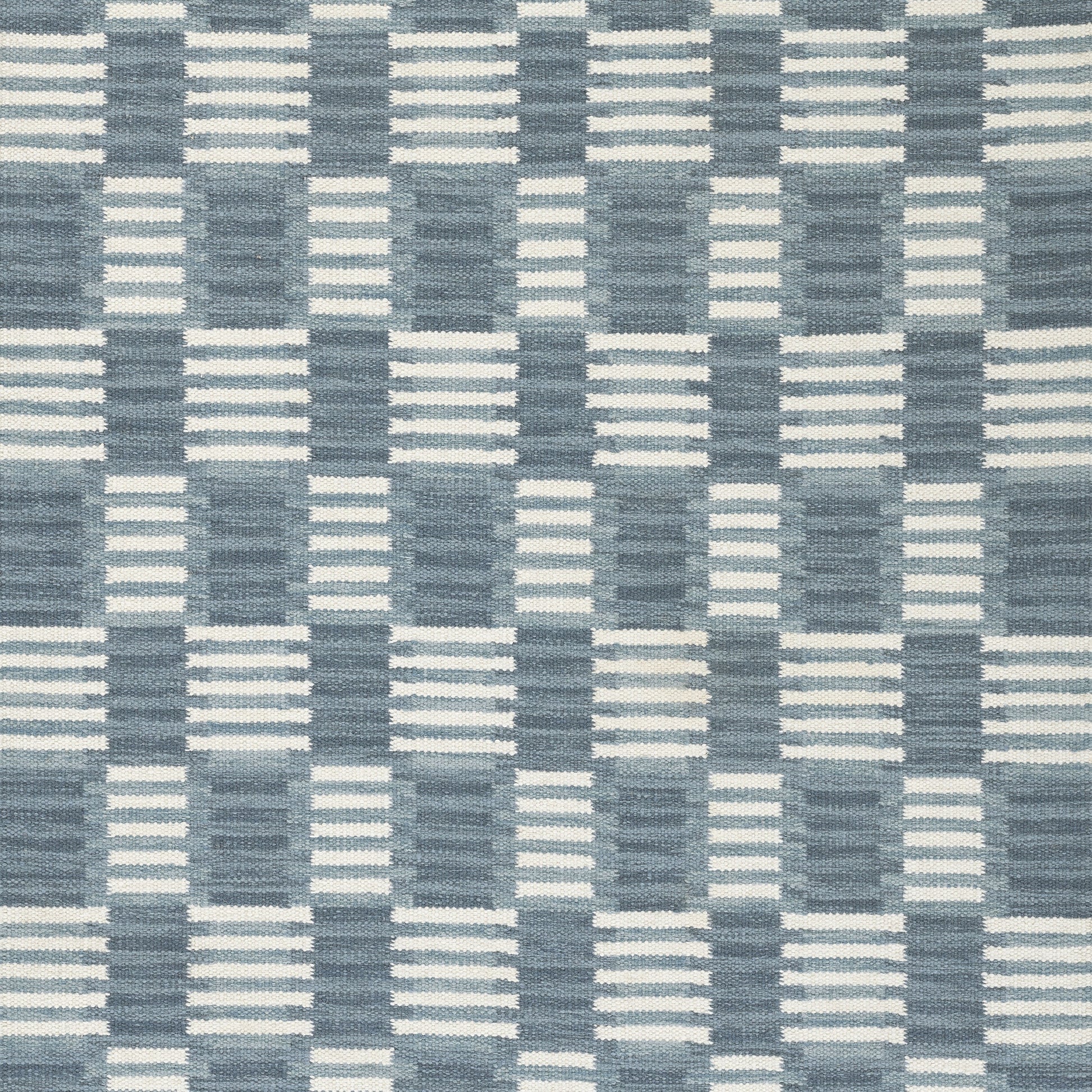 Blue and white woven checkerboard rug with striped blocks; Scandinavian-inspired home decor.