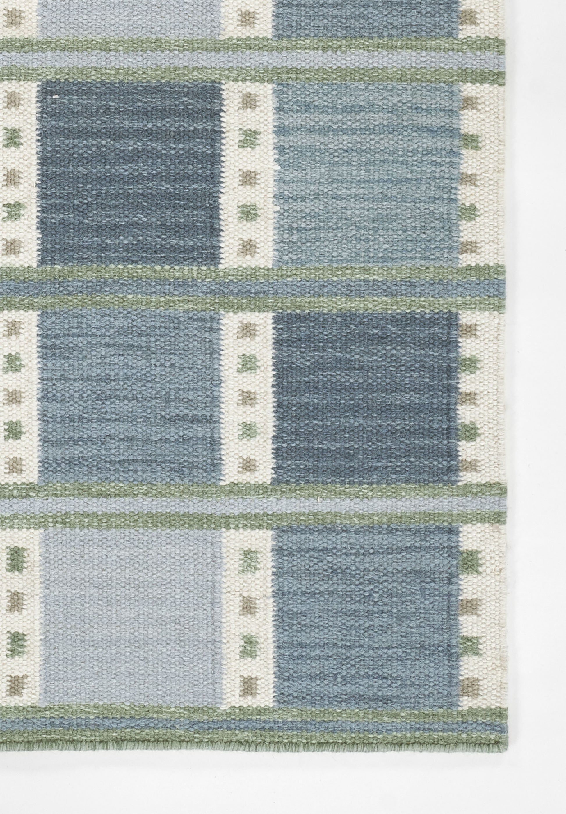 Blue Scandinavian woven rug with navy and light blue blocks, white vertical stripes with small green accents, green bands.