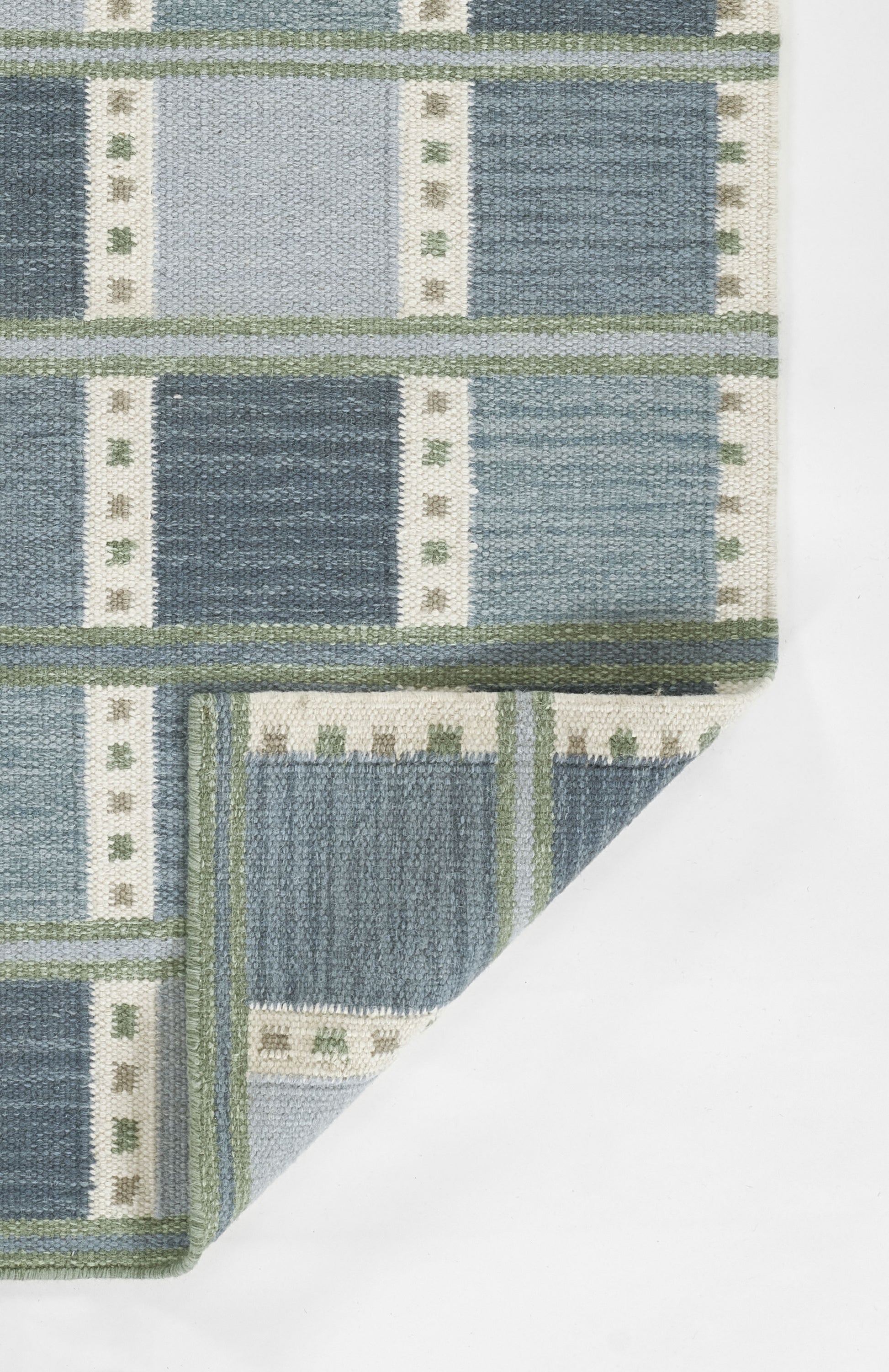 Scandinavian blue patterned rug with light and dark blue block panels, cream dotted borders, green trim; folded corner; 9' x 12'.