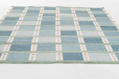 Blue plaid flat-weave rug with pale blue and white squares; fringed edge, ideal for living room decor.