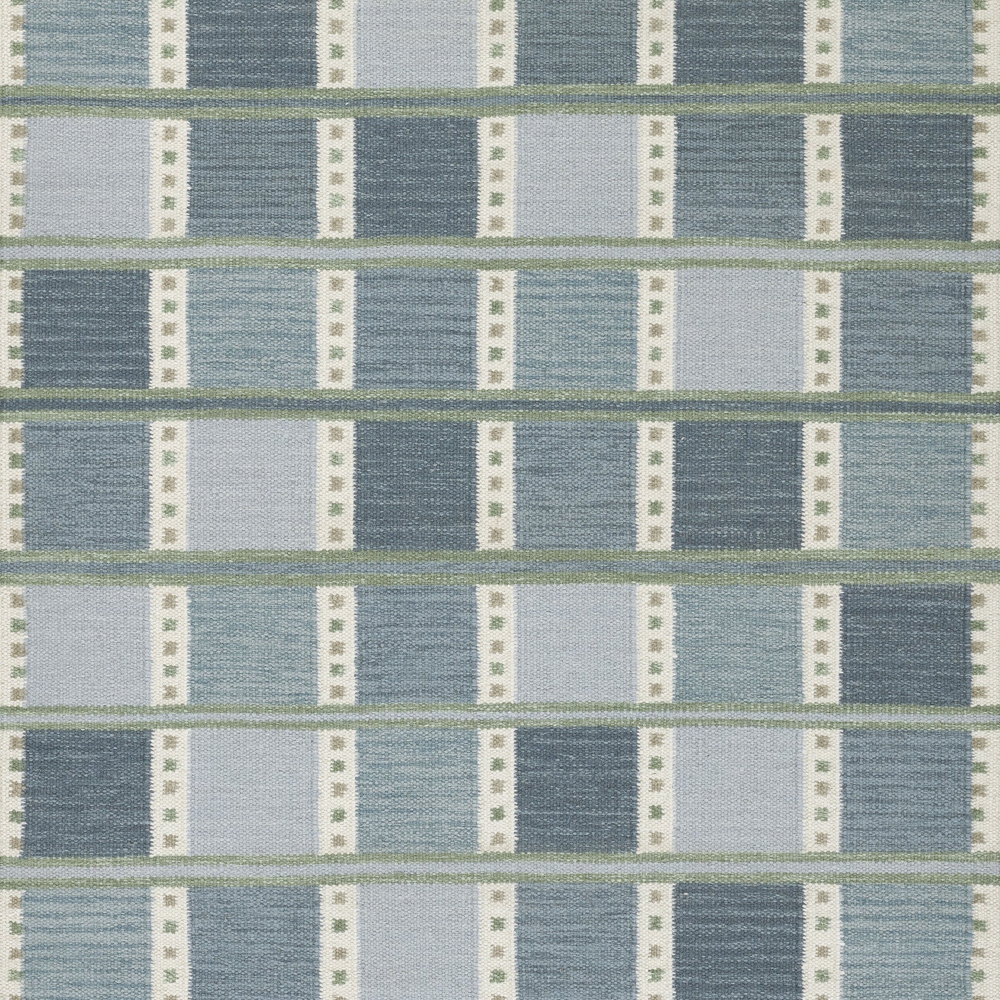Blue woven rug with alternating light and dark blue blocks, thin green lines, and white dotted vertical bars.