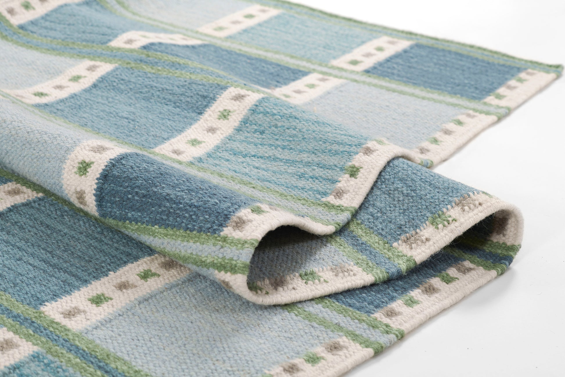 Rectangular rug in blue and teal stripes with white dotted borders; plush floor covering, folded; size 9' x 12'.