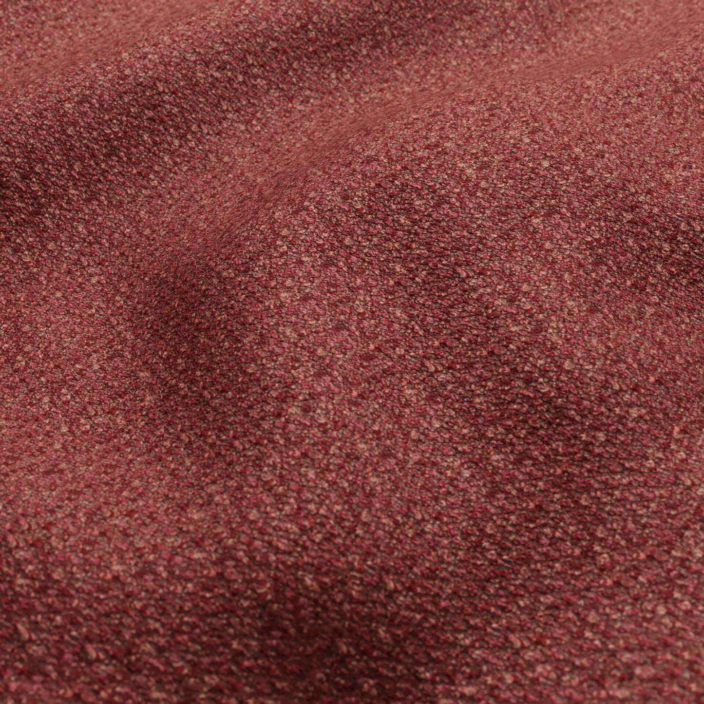 Close-up of burgundy boucle fabric texture with pink and blush tones.