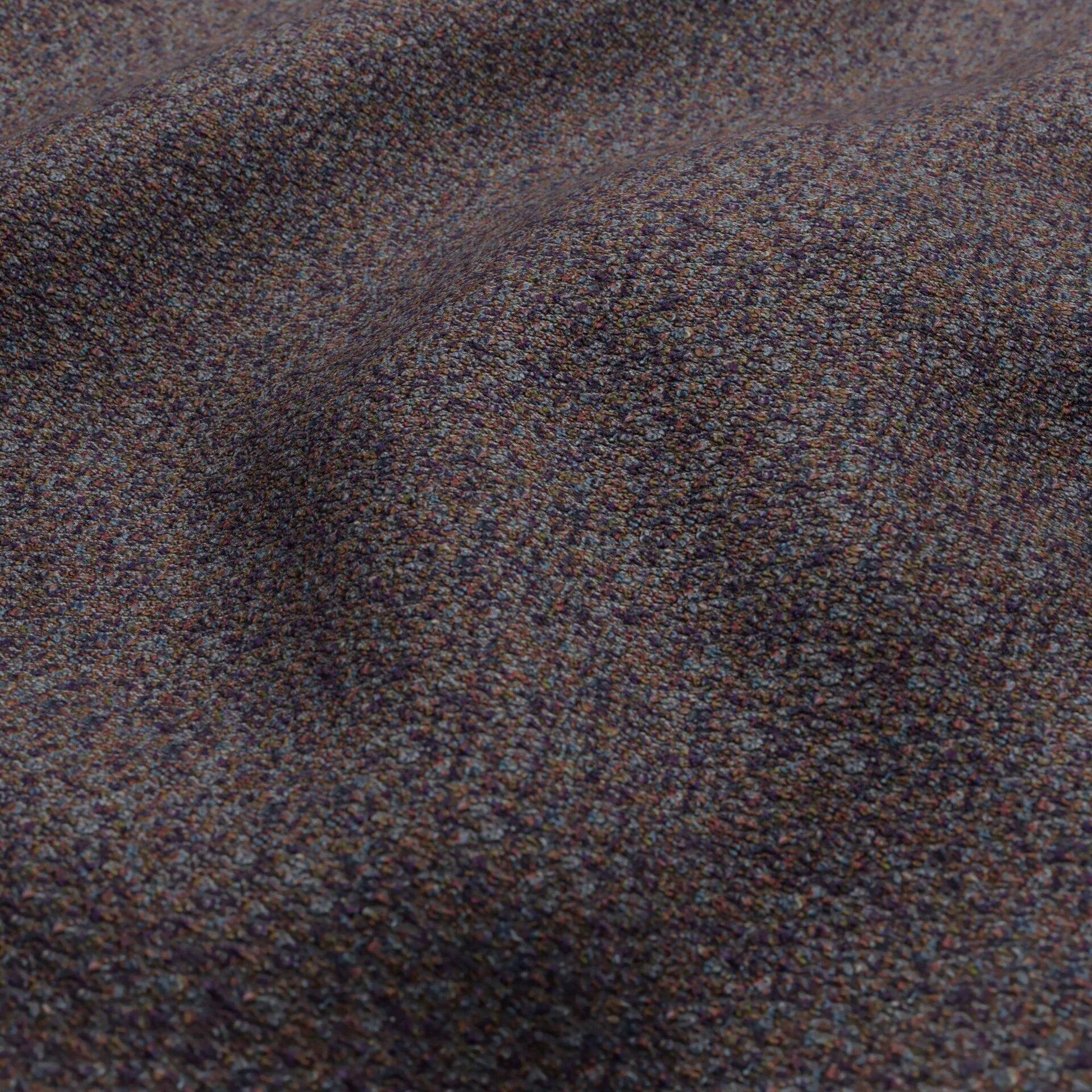 Close-up of bouclé fabric in dark blue, rust, olive green and plum tones, showing a textured surface with soft draped folds.