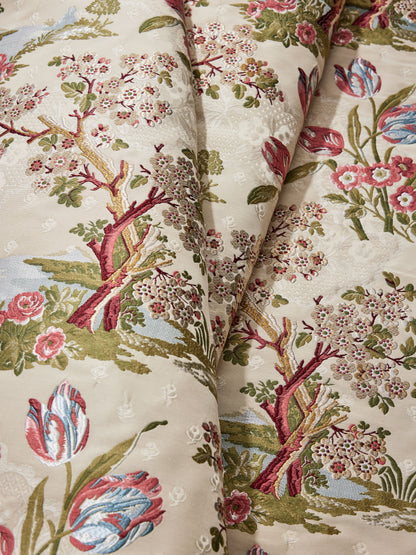 Cream damask upholstery fabric with multicolor floral & tree motif, pink blossoms, blue tulips, green leaves.