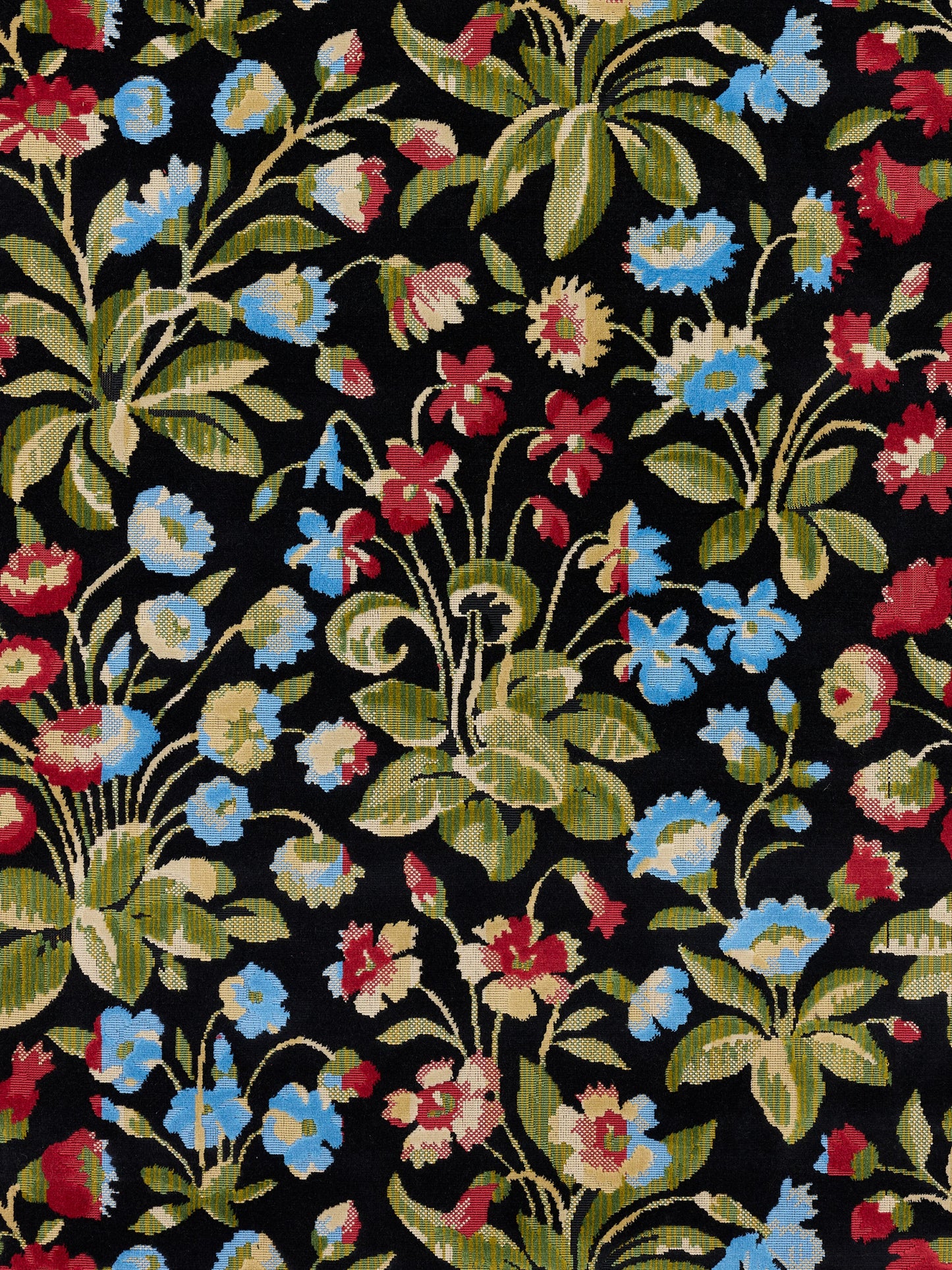 Floral tapestry fabric on black background with blue, red and cream flowers and green leaves.