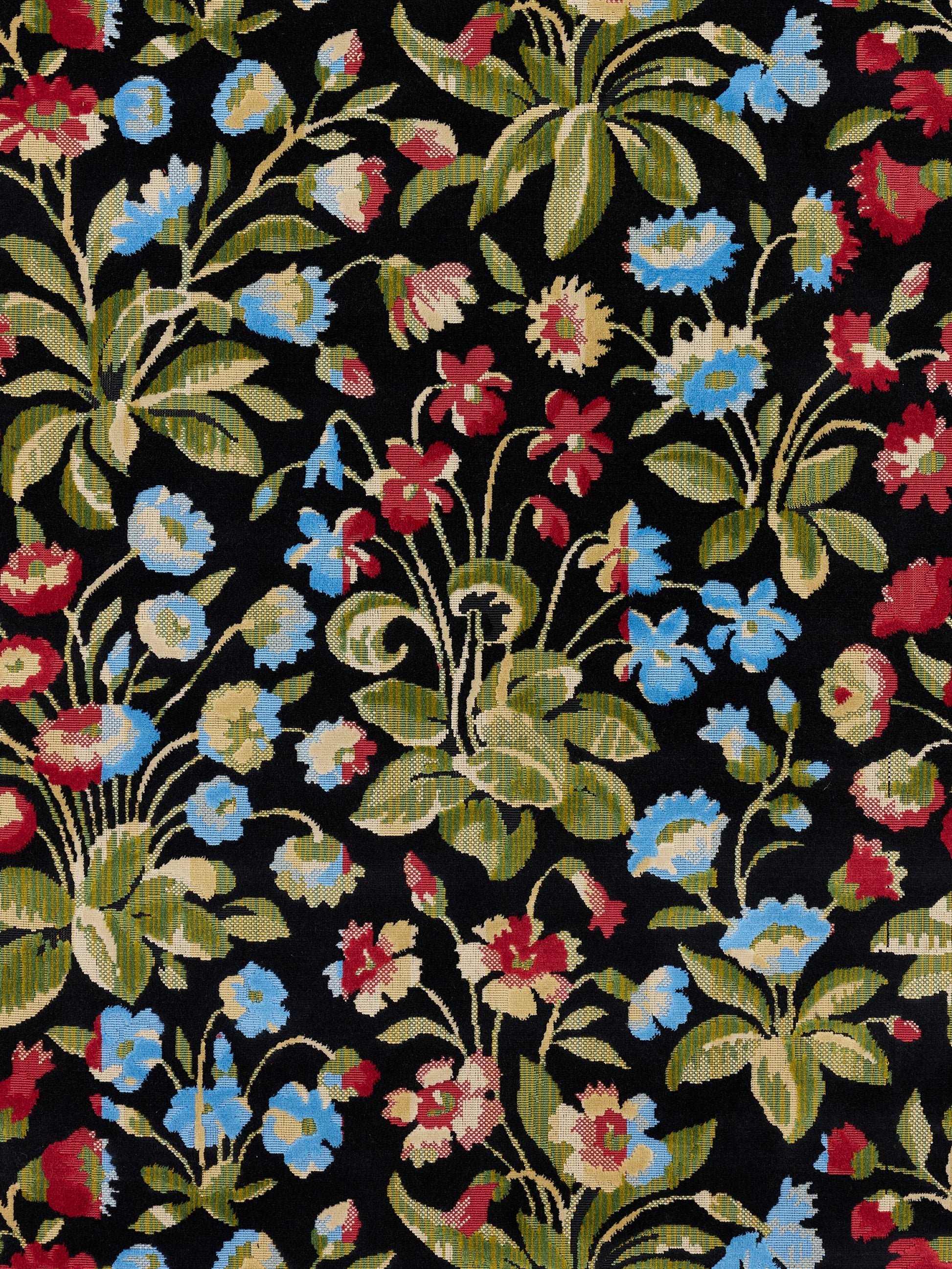 Floral tapestry fabric on black background with blue, red and cream flowers and green leaves.