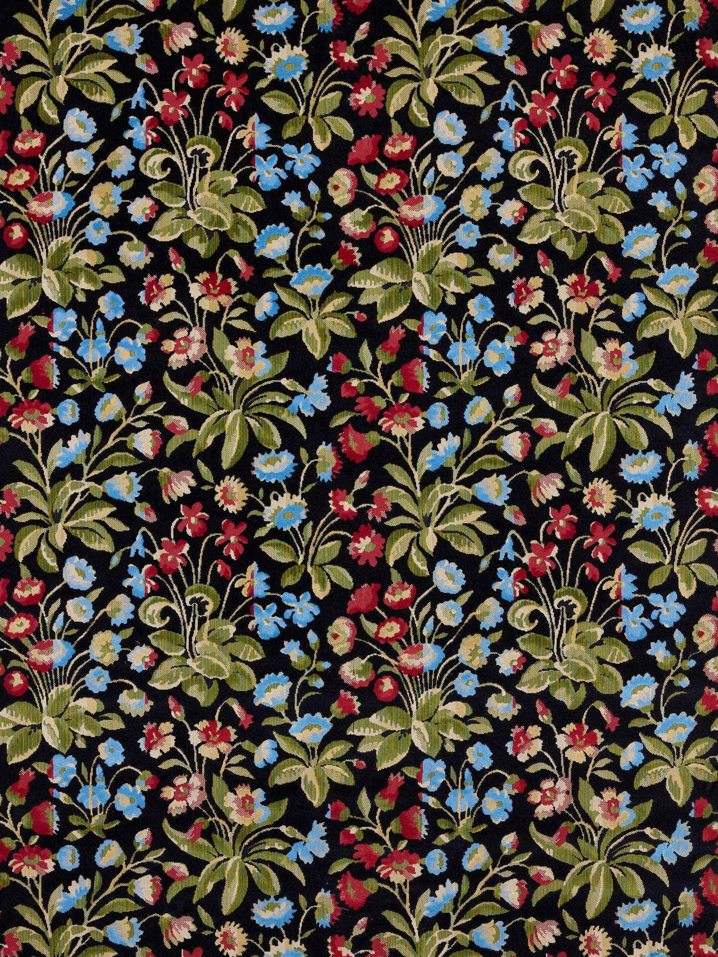 Black fabric with dense multicolor floral print in blue, red, pink flowers and green leaves, repeating botanical bouquets.