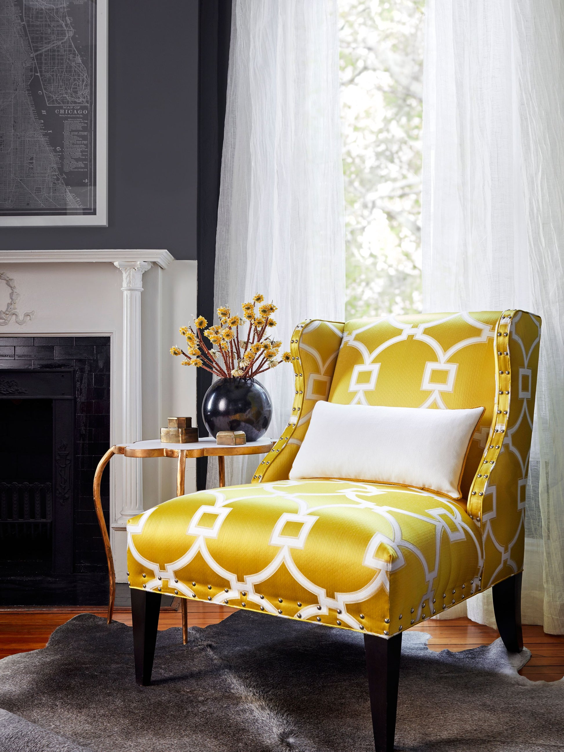 Yellow and white geometric upholstered armchair with nailhead trim, dark wood legs, and a white pillow.