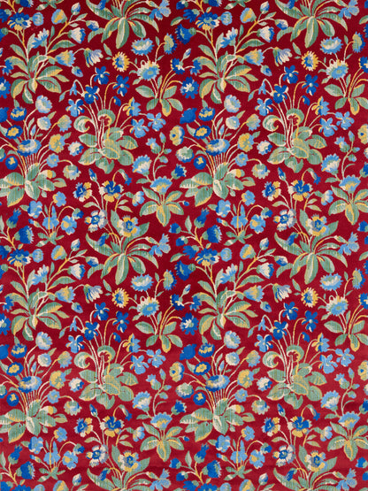 Red floral textile with blue and pale yellow flowers and green leaves in a vintage tropical pattern.