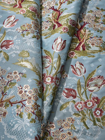 Light blue damask fabric with pink and cream flowers, red tulips, and green leaves in a jacquard tapestry pattern.