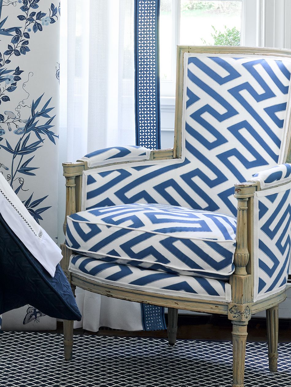 Vintage distressed wood armchair wrapped in blue-and-white geometric maze upholstery.
