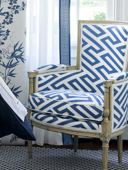 Vintage distressed wood armchair wrapped in blue-and-white geometric maze upholstery.
