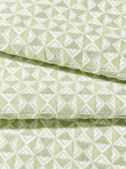 Mint-green fabric with white geometric triangles forming a diamond pattern; soft woven texture and folded layers.