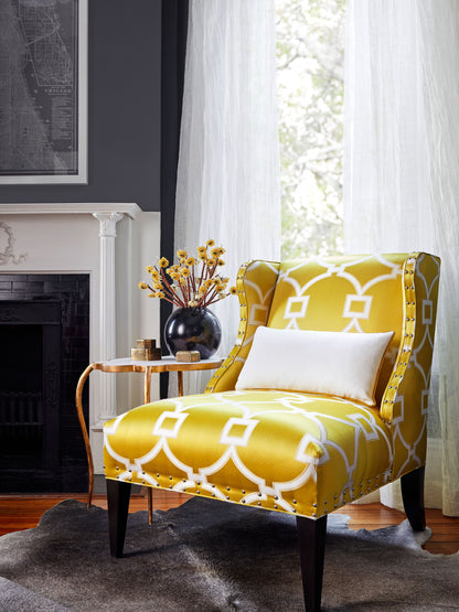 Accent chair upholstered in yellow circle fret fabric Forsythia with nailhead trim, white lumbar pillow, and dark wood legs.