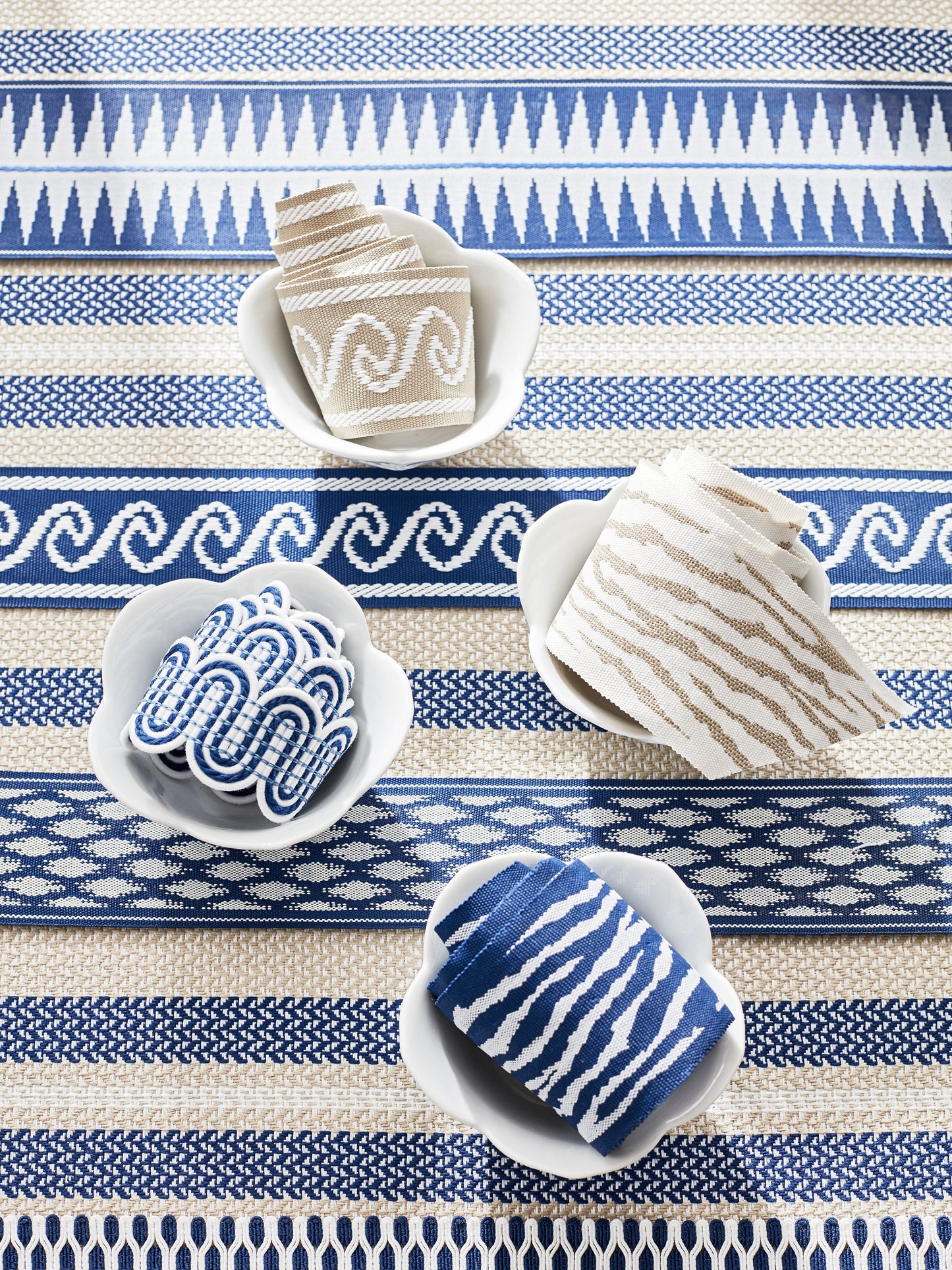 Blue & white patterned woven rug with geometric stripes; white bowls hold beige, gray, & blue ribbon trims.