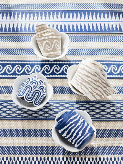 Blue and white patterned rug with bowls of rolled fabric napkins in beige and blue stripes.