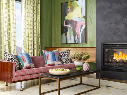 Red patterned mid-century sofa with leopard and geometric cushions, green wall, abstract painting, wood coffee table.