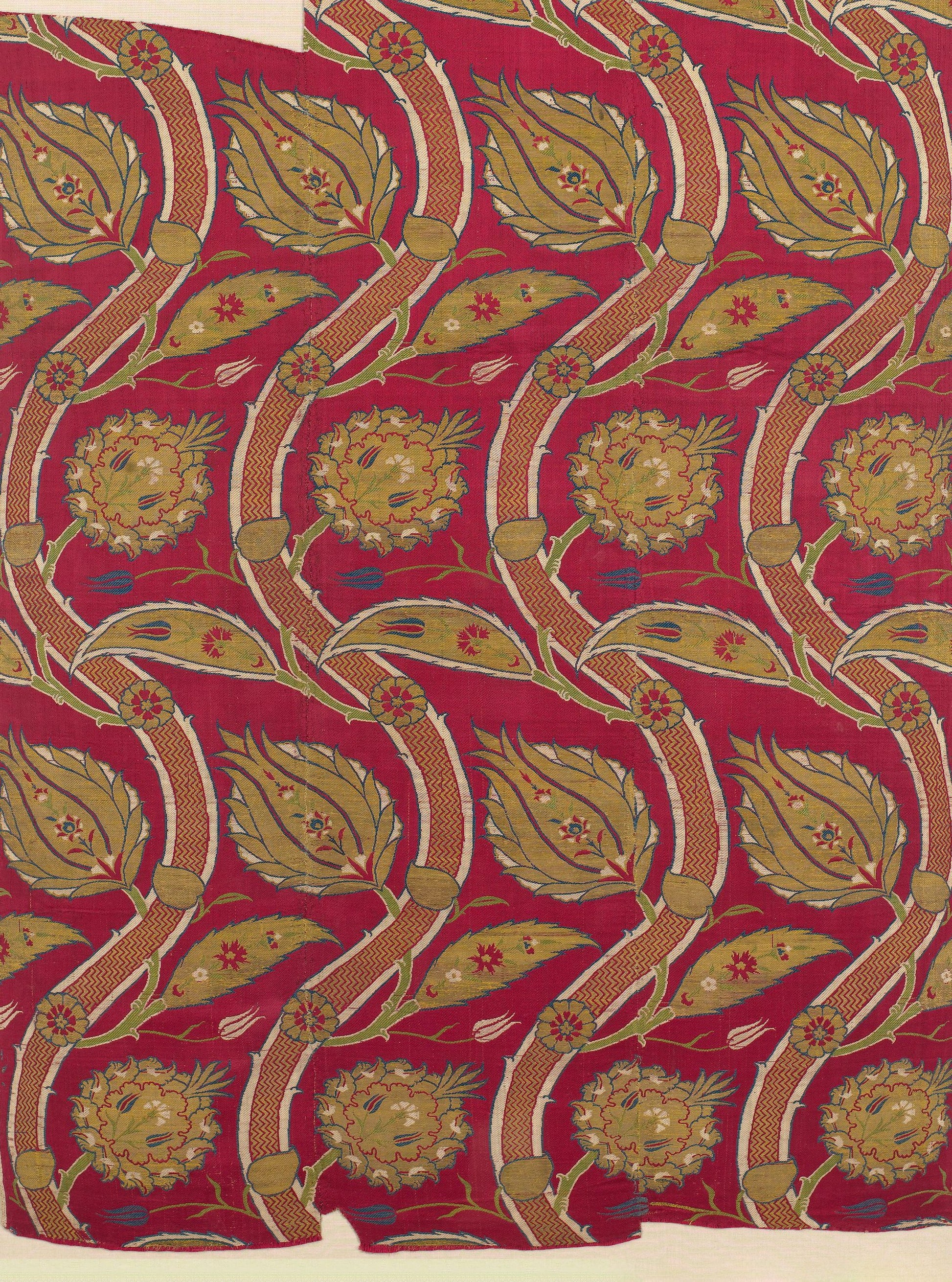 Red fabric with gold curved vines, olive leaves and round floral medallions; ornate repeating botanical upholstery print.