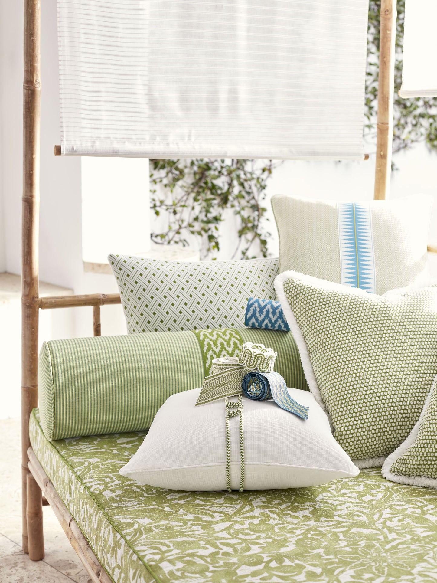 Outdoor bamboo daybed with green botanical cushions & blue-green accent pillows for al fresco lounging.
