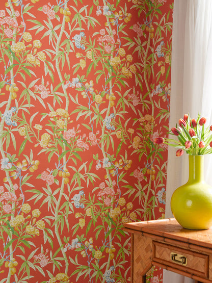 Bold coral floral wallpaper with green bamboo stems; lime vase with tulips on a wooden dresser beside sheer white curtains.