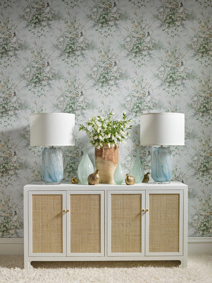 White console with four wicker-panel cabinets, blue glass lamps on each end, vase of white flowers, coastal chic decor.