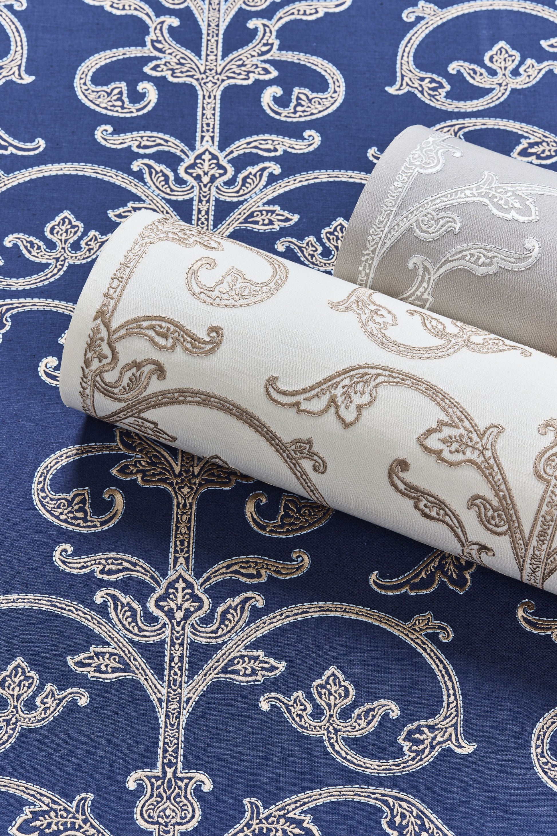 Damask wallpaper rolls in blue, white & gray tones with ornate scroll patterns for interior walls.