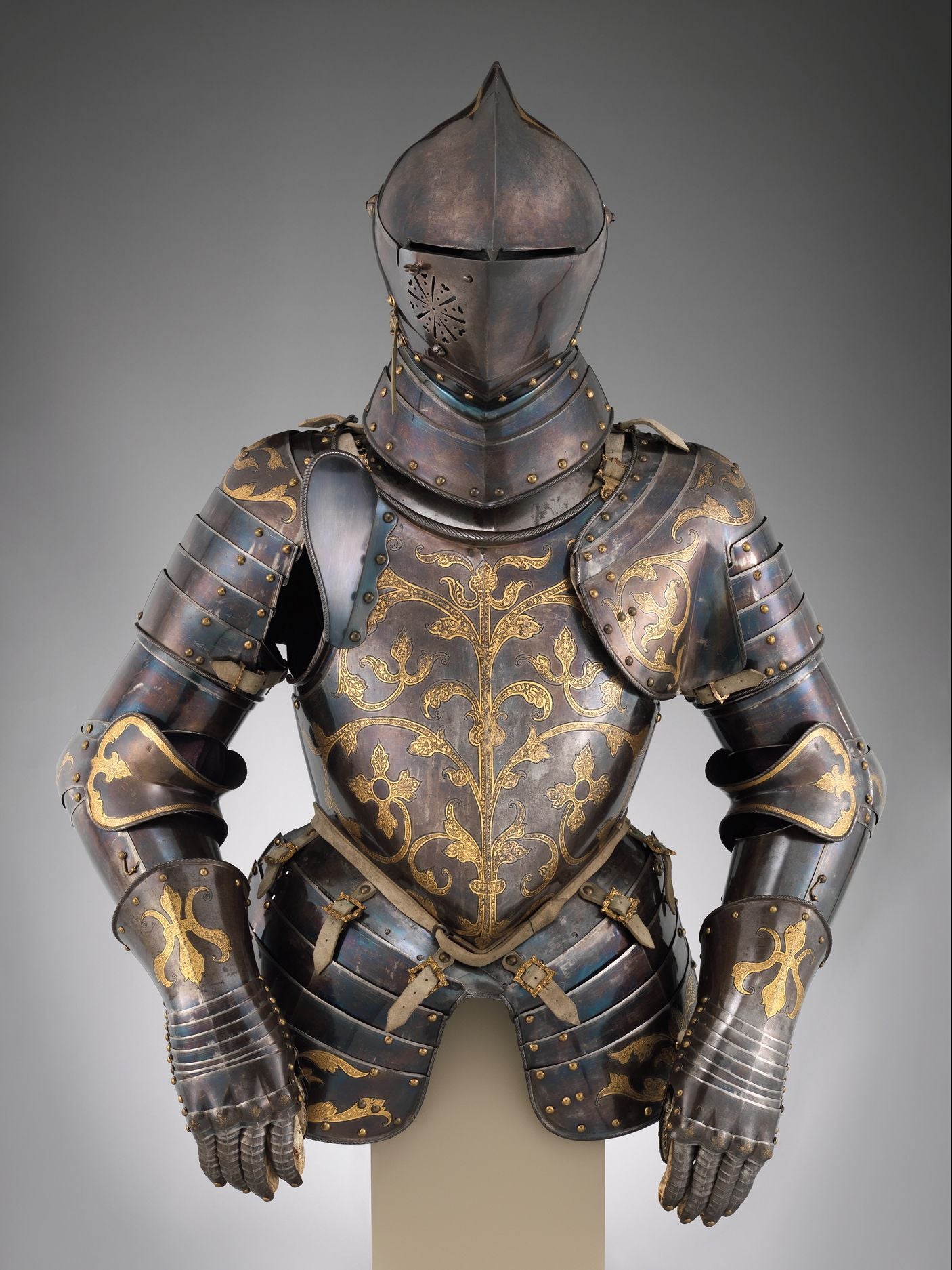 Ornate dark steel full plate knight's armor with gold vine engravings, helmet with visor, displayed on a bust.