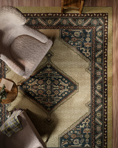 Beige oriental rug with navy blue medallions and burgundy border, paired with a plush beige chair and round coffee table.