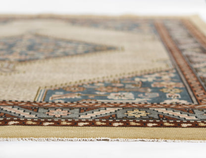 Beige Persian-style area rug with blue and brown geometric border, woven texture and fringed edges.