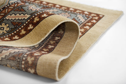 Beige and brown oriental rug with blue accents; geometric pattern, rolled edge, woven wool texture.