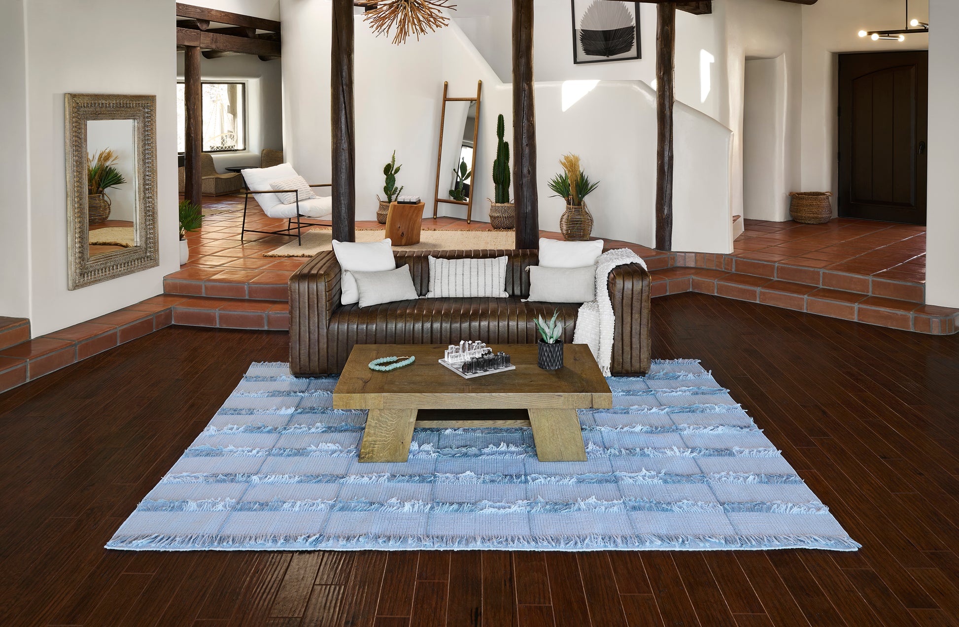Light blue and white striped textured area rug with fringe under a rustic coffee table in a modern boho living room.