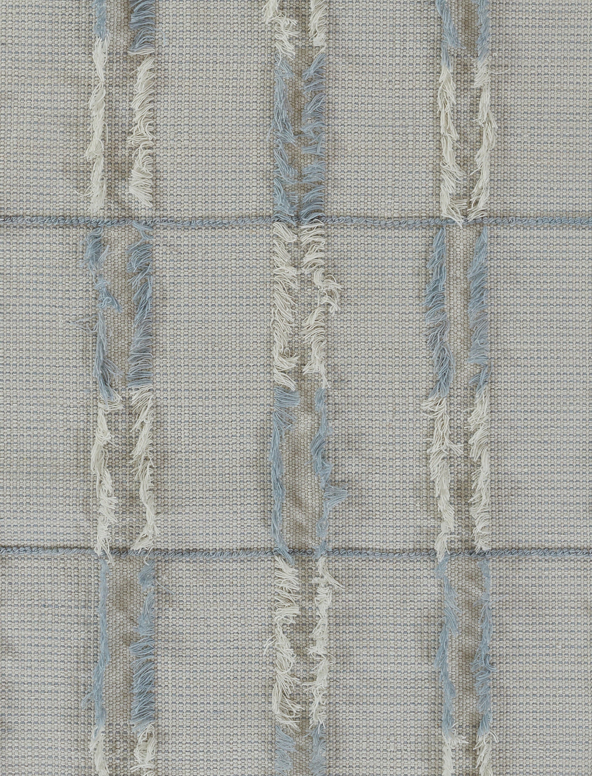 Beige woven rug-like textile with pale blue frayed vertical stripes and fringe, grid-pattern texture